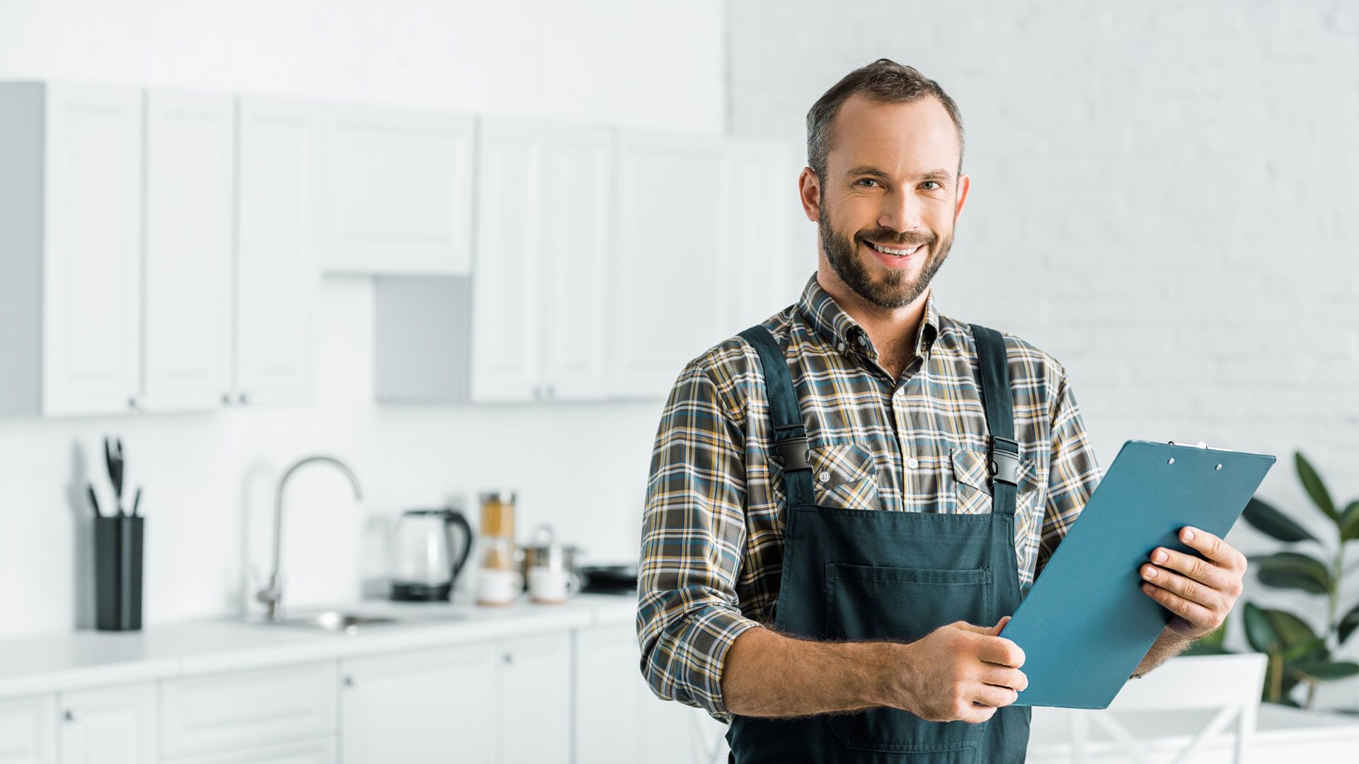 Mann im Blaumann mit Klemmbrett in Küche